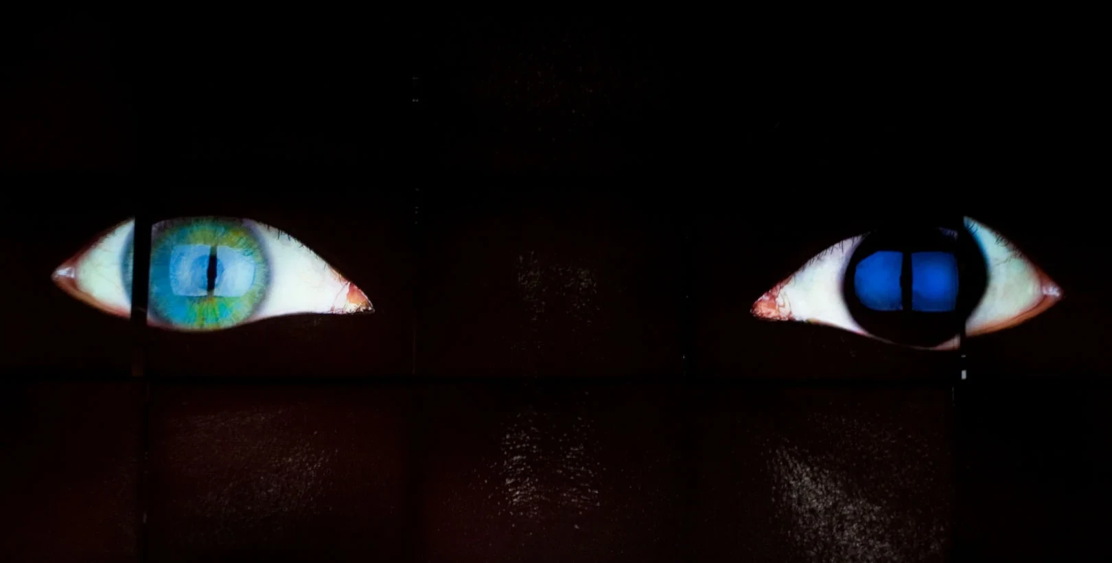Two projected eyes on a dark wall