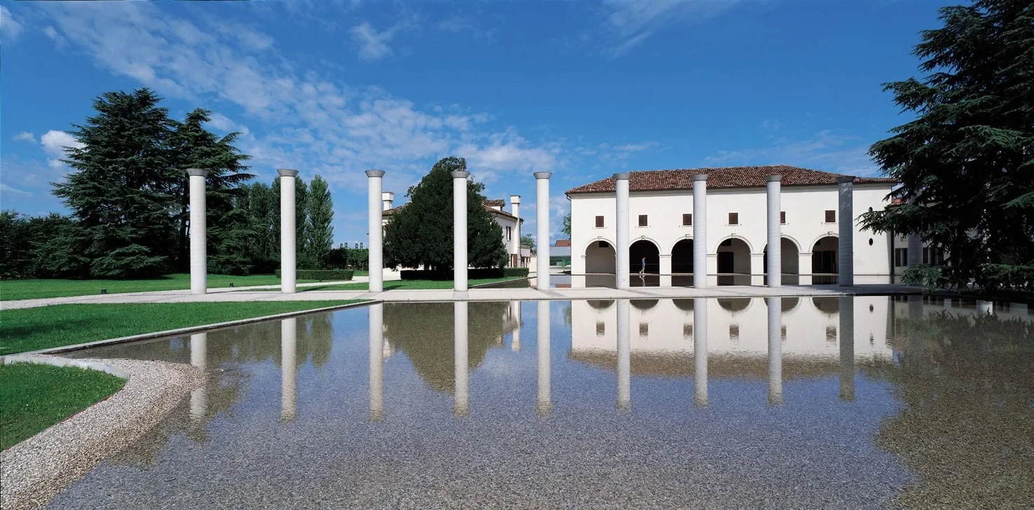 The Fabrica villa: white columns reflected in a long still pool