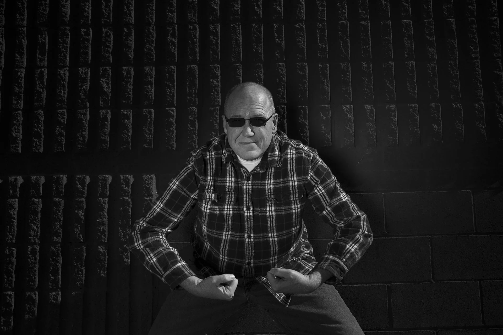 A black and white portrait of a man with arthritic hands