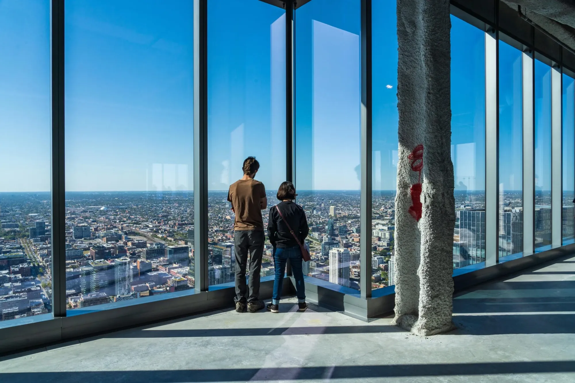 Two visitors look out over Chicago from a high-rise window